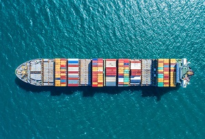 Cargo ship with cargo containers moving across open water.