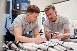 Engineer Showing Apprentice How To Measure for CAD Drawings.