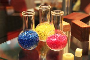 Colored polymer granules in glass flasks in factory.