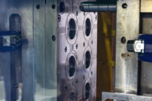 Close up of the open cavity of a steel mold in an injection molding machine.