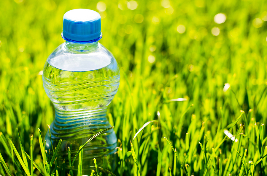 A clear bottle made of transparent thermoplastics on top of grass