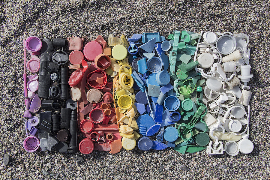 A gradient of different colored plastics arranged int he order of a rainbow on sand, used to signify discoloration in plastic injection molding.