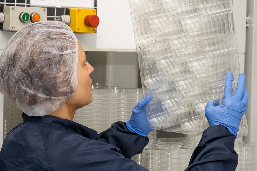 A female technician inspecting plastic packages generated by thermoforming 