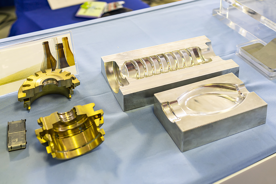 Two bottle-shaped plastic injection molds laying side by side meant to demonstrate prototype tooling in injection molding.