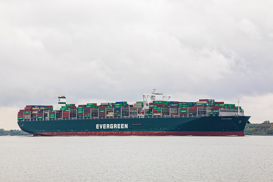 A side shot of the Ever Given with "Evergreen" printed on the side floating in a canal, used to represent the fragility of logistics underlined by the Ever Given.