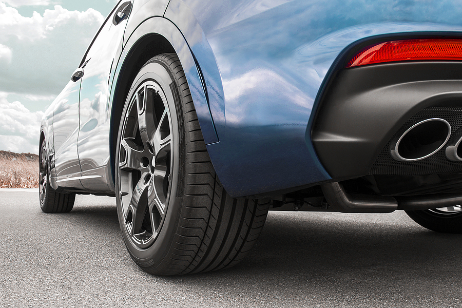 A close-up of the rear of a blue car depicting a plastic plate surrounding the exhaust pipe.