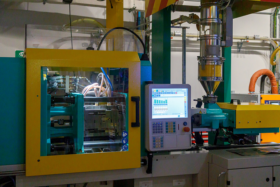 A picturing of a green and yellow plastic injection molding machine with a computerized display.