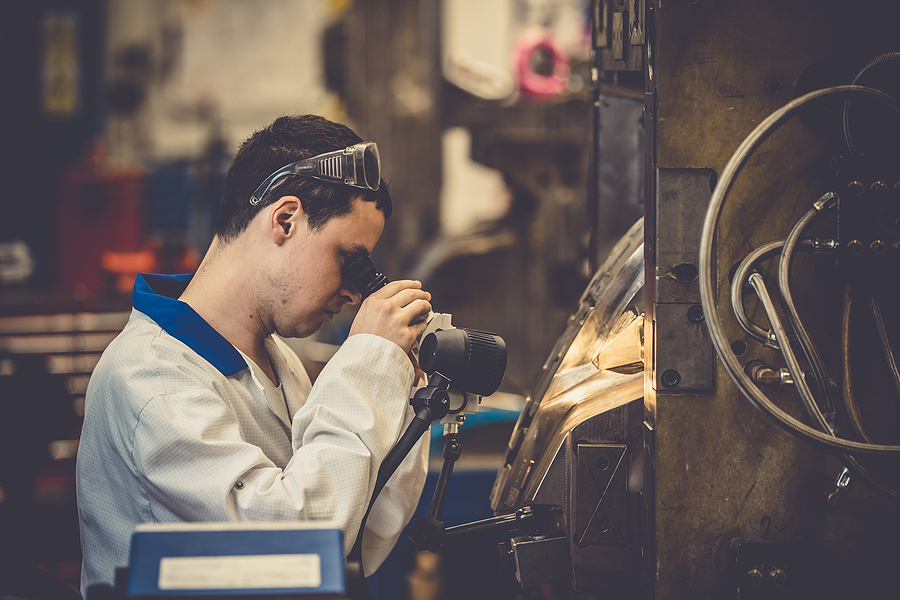 An injection molder using a microscope to inspect the polished interior of an injection mold.