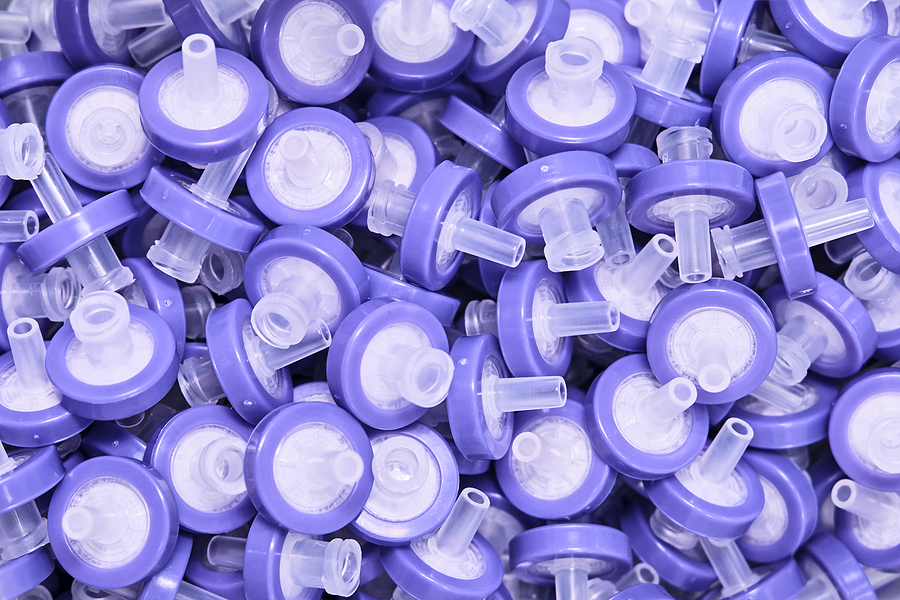 A pile of purple syringe PTFE membrane filters meant to signify alternative thermoplastics to PTFE
