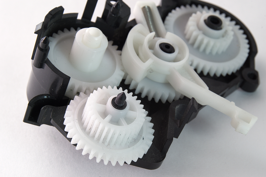 White plastic spur gears interconnected in black, plastic housing designed through plastic injection molding.