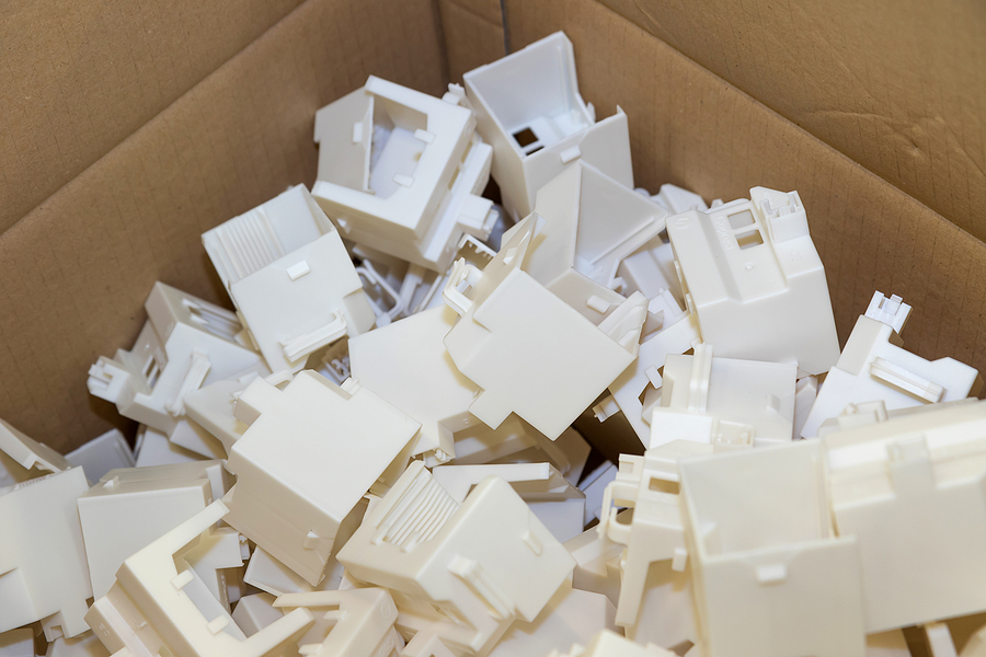A cardboard box full of white, plastic electrical boxes created using plastic injection molding.