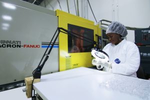 Midstate Mold employee in cleanroom gear performing quality control on injection molded plastic parts.